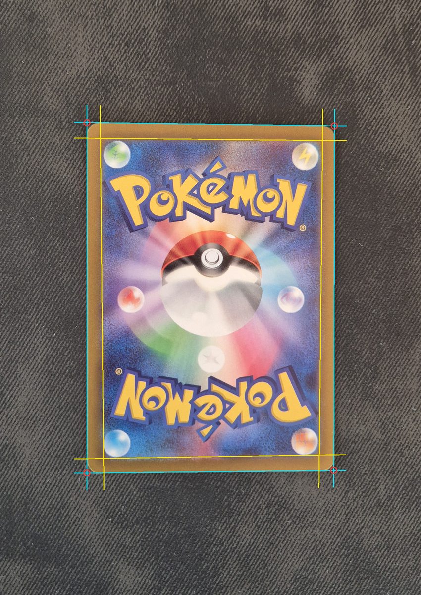 Photo of the back of a Japanese Pokémon card on dark cloth with the detected corners, cut lines and print lines drawn over it